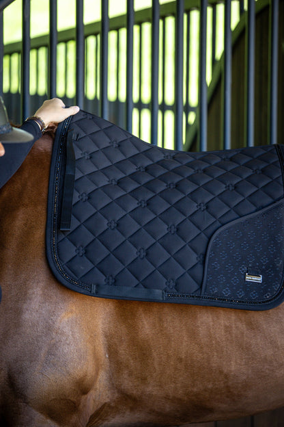 Black quilted saddle pad on a horse with a blurred background