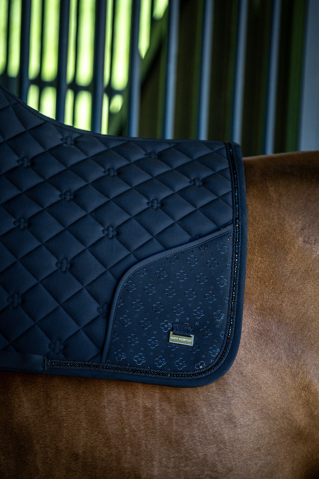 Black quilted saddle pad on a horse's back with a blurred background